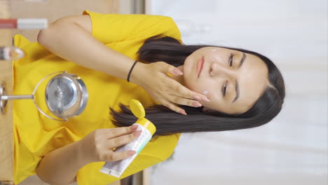 Vertical-video-of-The-young-woman-who-puts-cream-on-her-face.-Skin-beauty.